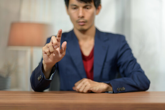 Man in business suit gesturing with finger while sitting at desk in modern office environment