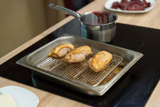 Grilled chicken breasts on wire cooling rack with sauce pot for gourmet dinner meal preparation and cooking concept