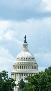United States Capitol Dome Framed by Green Trees Under Dramatic Cloudy Sky