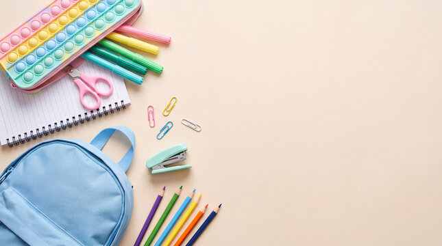 Back to school flat lay background with a blue backpack, colorful pencils, markers, notebook, and stationery items with copy space.