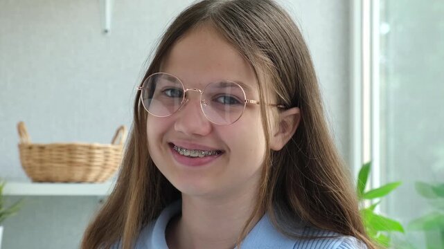 Smiling teen girl in glasses with metal dental braces. Happy female teenager looking at camera