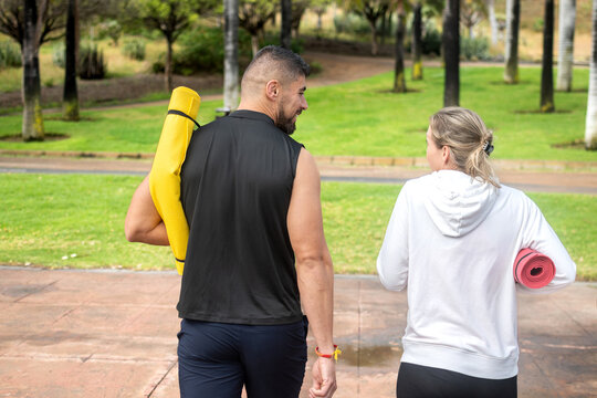 Friends walking with yoga mats in the park