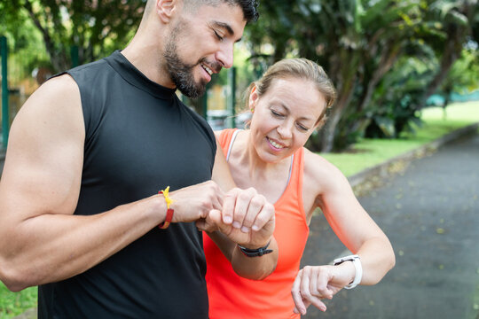 Fitness trainer checking smartwatch with client