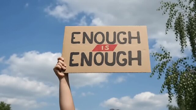 People holding protest sign saying enough is enough outdoors.