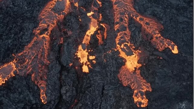 Molten lava flowing through volcanic terrain at night.