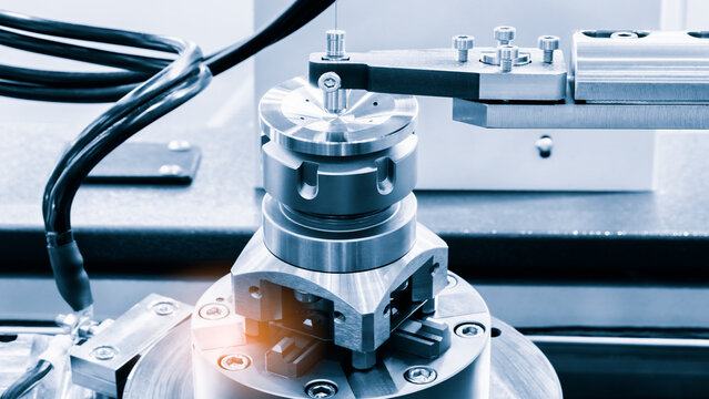 Close-up of metallic mechanical assembly. Cylindrical component secured by screws and bolts. Electrical wires connected to device. Industrial precision machine part visible