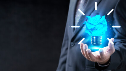 Businessman holding a glowing blue crumpled paper light bulb, representing creative business ideas and innovation. Concept of Idea © Leo Lintang