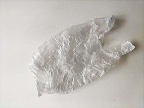 Crumpled transparent plastic shopping bag isolated on a white background, representing plastic pollution and environmental waste.