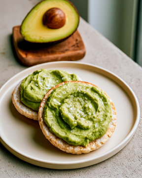 Fresh avocado spread on rice cakes with sea salt flakes on white plate, healthy snack concept