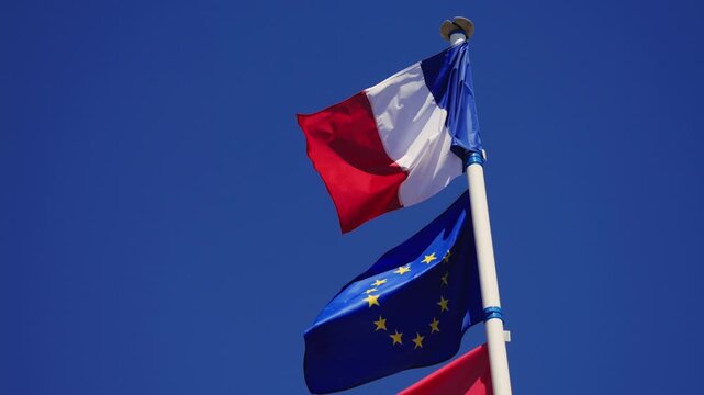 French and European Union flags waving against a clear blue sky. High quality 4k footage