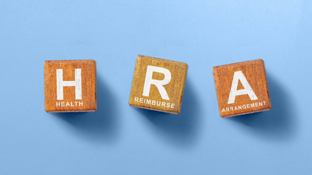 Wooden letter blocks spelling HRA (Health Reimbursement Arrangement) on a blue background. Concept of Reimburse