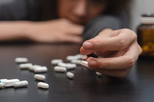 Anti drug, drug addict asian young woman, girl hand reaching for syringe, medicament with narcotic on table at home, abuse overdose. Sick pain of health, unhealthy people. Suicide depressed or despair
