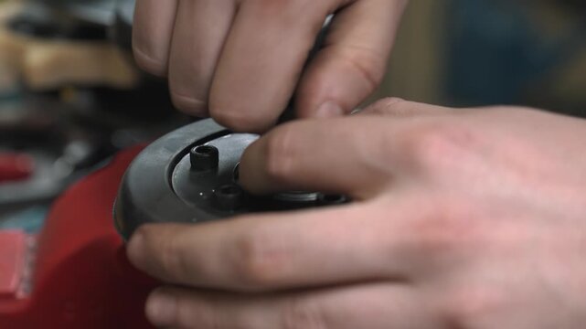 A worker secures the steel base of a rubber roller with bolts whose threads have been lubricated with blue thread locking fluid.