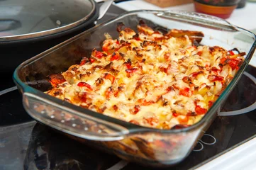 A Baked Vegetable Casserole of Cauliflower made with Potato, Sweet Bell Red Pepper, Chicken, Cheese and Tomatoes in Glass Baking Dish. Selective Focus. © troyka