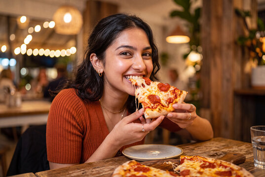 Woman enjoying delicious pizza in restaurant