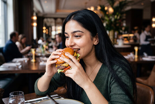 Woman eating sandwich in cozy restaurant