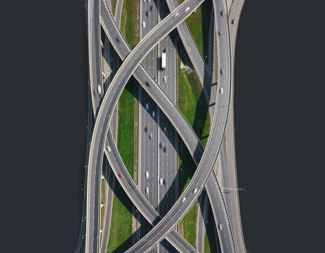 Aerial top-down drone view of a complex highway interchange and intersecting road network with moving cars.