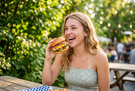 Woman happily eating donut outdoors in summer