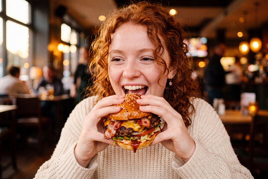 Woman happily eating a burger at night