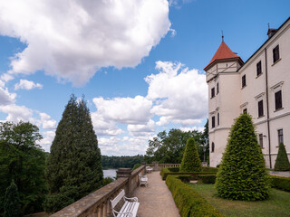 Garden terrace of Konopiště Castle near Benešov, Czech Republic, overlooking landscaped park and lake beneath a blue sky with dramatic clouds. Historic castle gardens in summer. © Marek