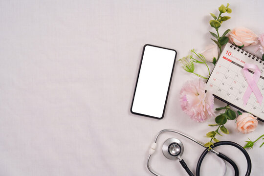 Breast cancer awareness concept with blank smartphone screen calendar stethoscope and pink ribbon