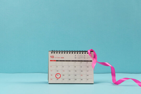 Desk calendar with pink ribbon on blue background for breast cancer awareness month