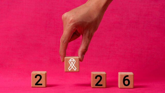 Hand arranging wooden blocks to spell 2026 year for breast cancer awareness campaign