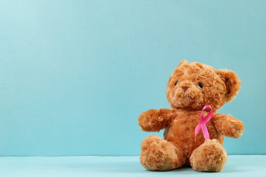 Teddy bear with pink ribbon on blue background for breast cancer awareness concept