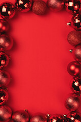 Vibrant red Christmas ornament border on matching red background, various bauble textures. Perfect festive frame for holiday greetings and text © MariiaDemchenko