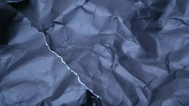 Abstract background of dark blue crumpled paper with a torn edge.