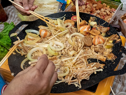 Street Food Stir Fry with Mushrooms, Chicken, Sausages, and Onions on Hot Griddle
