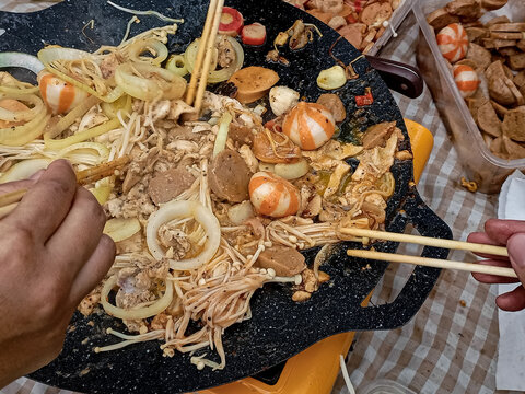 Street Food Stir Fry with Mushrooms, Chicken, Sausages, and Onions on Hot Griddle