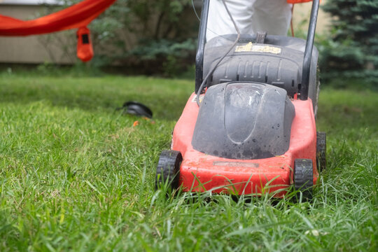 Front view of red lawn mower working through tall grass in a private garden