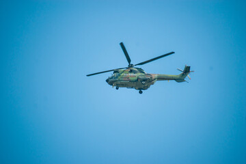 Military helicopter in flight against a bright blue sky. Dynamic aviation scene highlighting maneuverability, strength, and modern defense aircraft. © Max Asrory