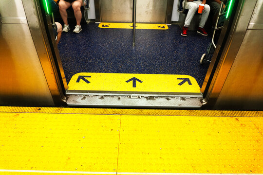 High-angle view of subway train doors opening at a station platform, featuring clear directional arrows on the yellow floor, emphasizing daily urban commute and public transit.
