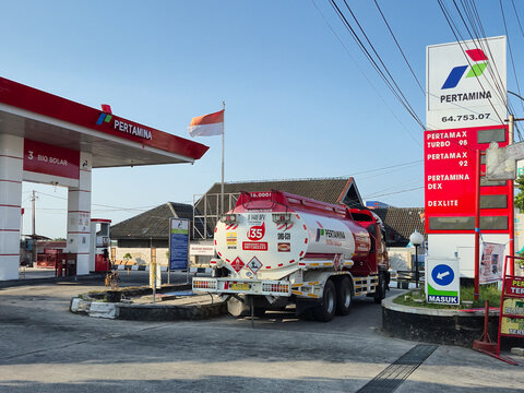 Logo of the Pertamina brand; fuel tanker truck refilling a gas station in Indonesia, representing energy supply and transportation.