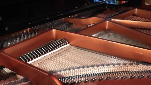 Detailed interior view of grand piano showing copper strings, curved wooden rim, metal plate, and warm amber lighting, creating rich gloss, fine texture, and refined classical mood