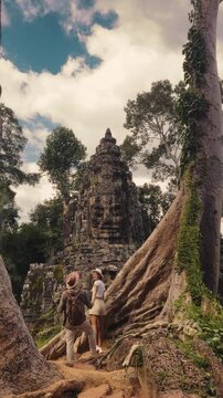 Fashionable Couple Standing By Giant Tree Roots At Victory Gate Angkor Thom