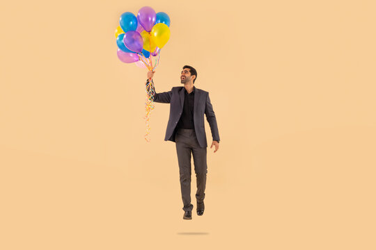 Happy businessman flying with air balloons