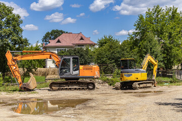 Orange Tracked Excavators Parked on Earthworks Construction Site © Iuliana