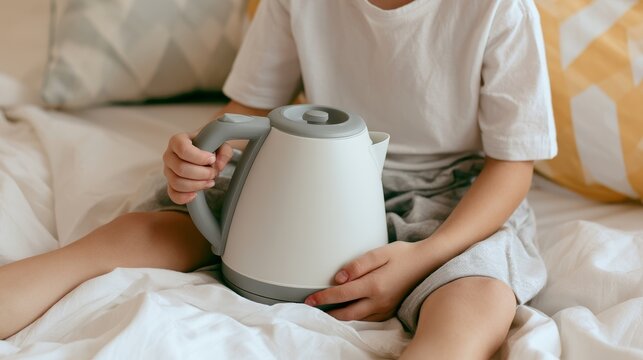 Child holding hot electric kettle at home, showing dangerous situation with burn risk, household accident prevention, safety awareness and protection concerns in domestic environment