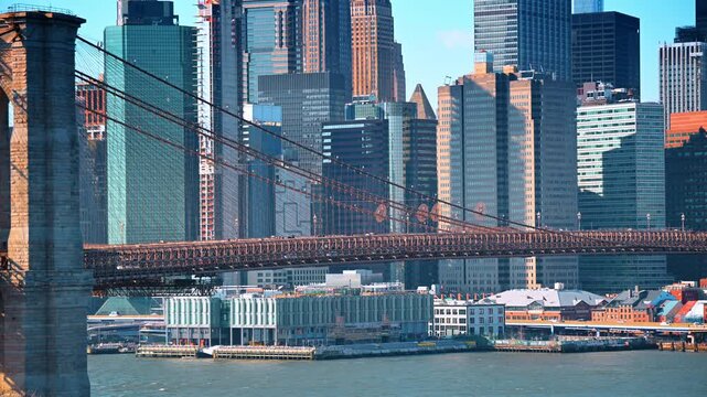 Brooklyn Bridge against Lower Manhattan skyline. Stone towers and suspension cables frame dense waterfront high rises in clear daylight.