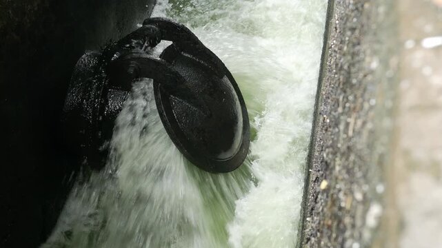 Iron Sluice Valve with Powerful Green Water Splash Close-Up