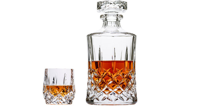 Crystal whiskey decanter and glass filled with amber liquid, isolated on transparent background
