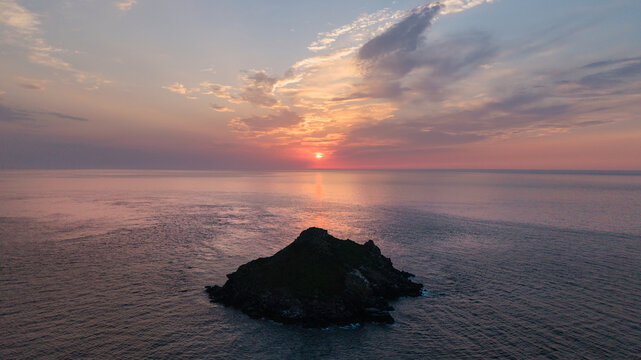 Beautiful drone landscape image of Pentire Headland and The Rumps in Cornwall and surrounding countryside during colorful Summer sunset