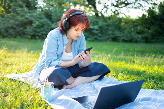 Young female student studying online with laptop outdoors in park.