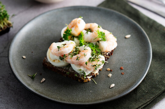 Healthy shrimp and egg smorrebrod garnished with fresh greens.