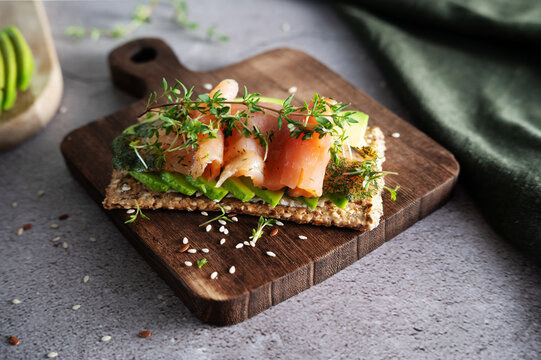 Multi-grain crispbread sandwich with cream cheese, avocado, and salmon.