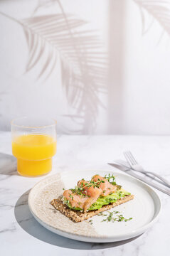 Sunlit breakfast plate with salmon crispbread and fresh orange juice.