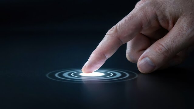 Human finger touching a glowing circular interface on a dark surface creating light ripples and digital waves in a futuristic technology setting